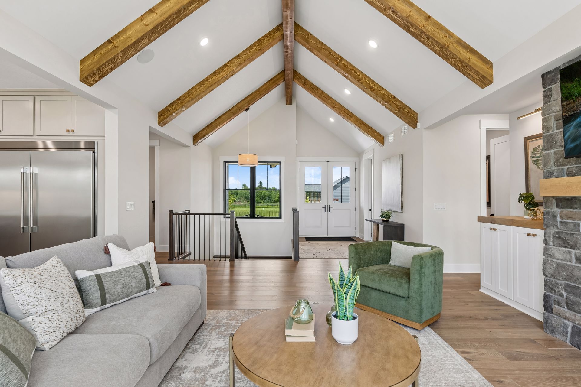 Vaulted great room with exposed wood beams and open staircase